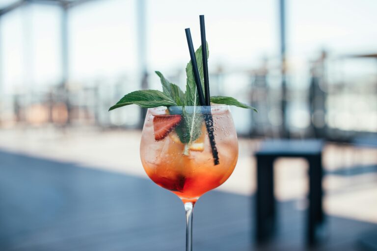 Chilled cocktail with mint and fruit garnish on a sunny rooftop bar.